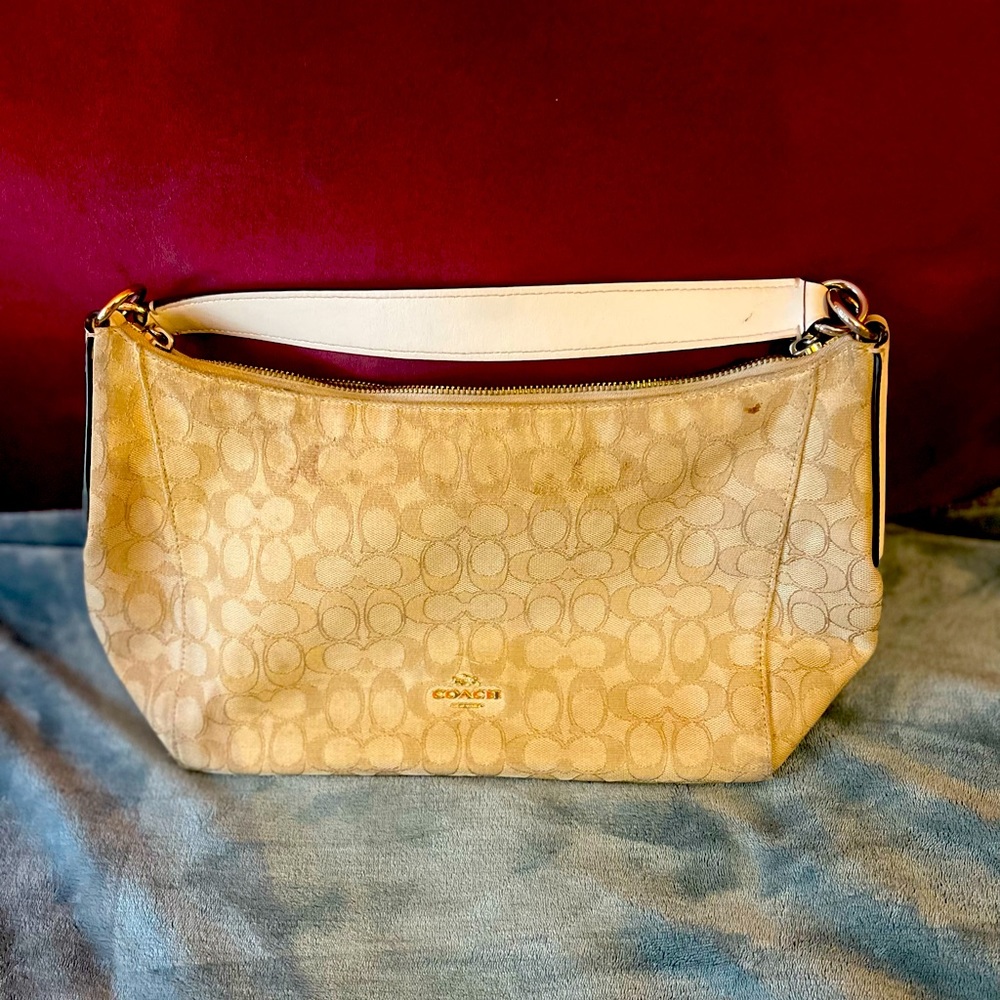 This is a tan stylist coach bag with a stap